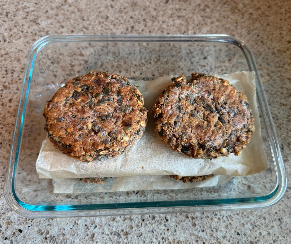Baked pinto bean and mushroom burgers stored in a freezer-safe container with parchment paper between layers Baked pinto bean and mushroom burgers stored in a freezer-safe container with parchment paper between layers