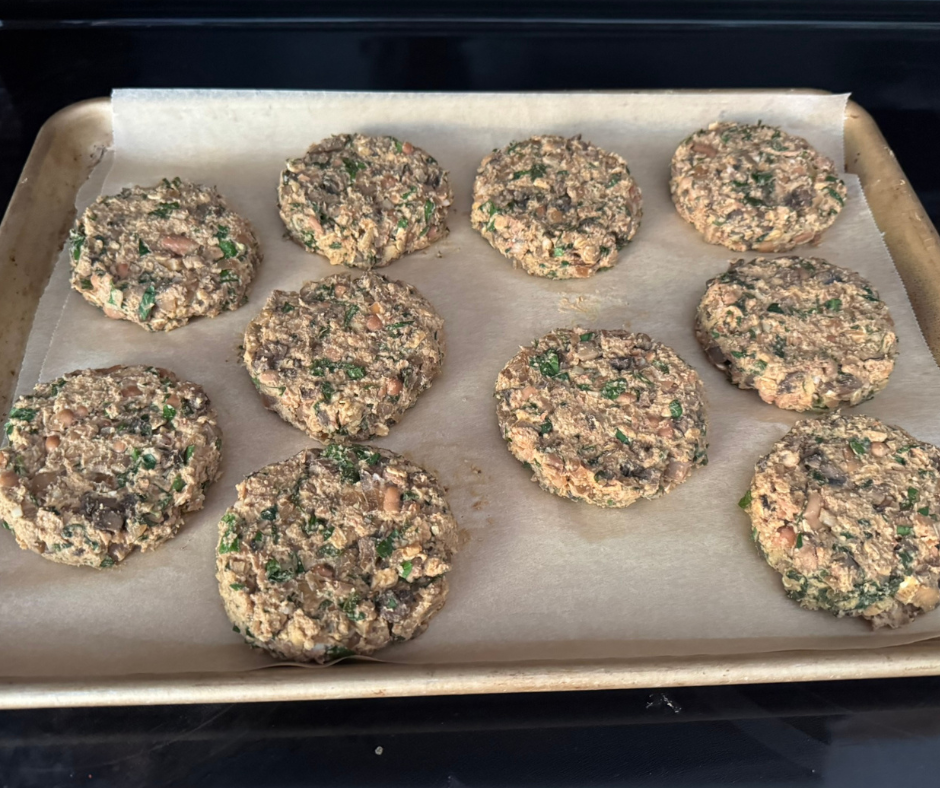 Ten shaped pinto bean and mushroom burger patties on a parchment-lined baking sheet, ready for the oven Ten shaped pinto bean and mushroom burger patties on a parchment-lined baking sheet, ready for the oven