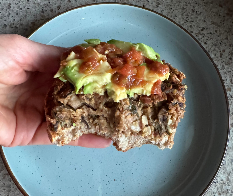 Close-up of a bitten pinto bean and mushroom burger topped with avocado and salsa, showing the hearty texture inside Close-up of a bitten pinto bean and mushroom burger topped with avocado and salsa, showing the hearty texture inside