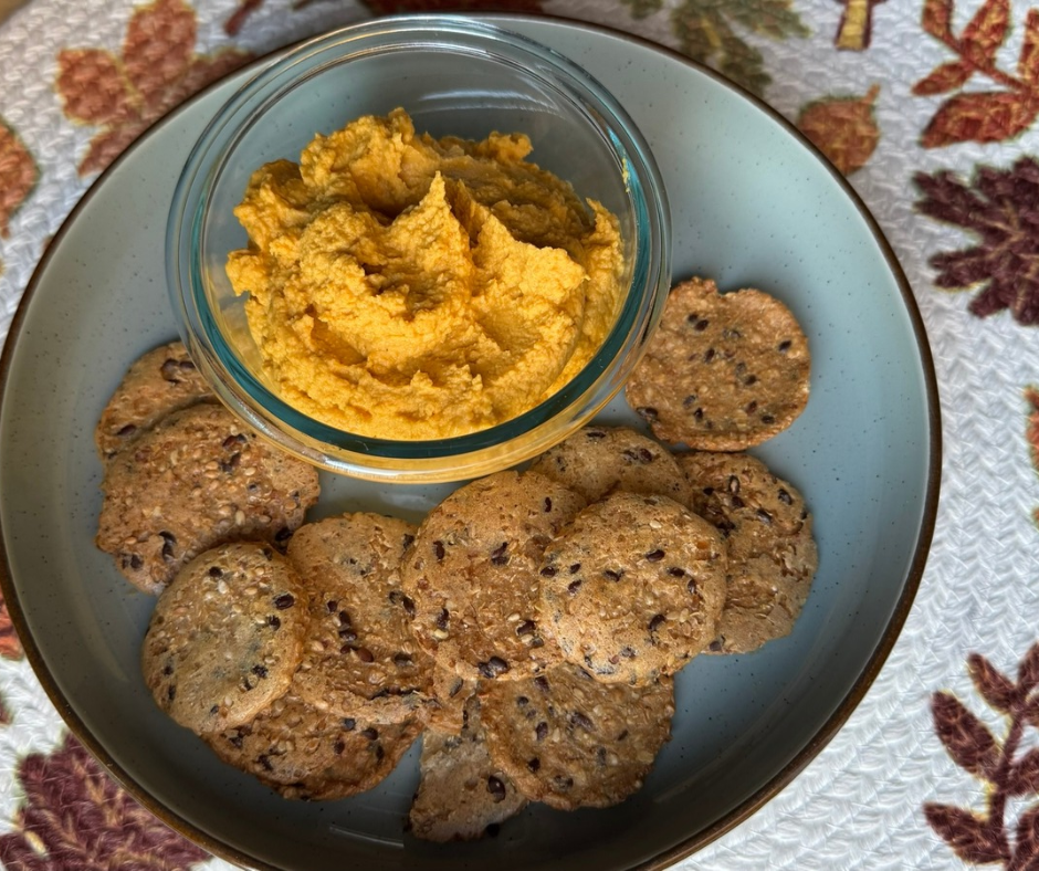 Homemade pumpkin hummus in a glass bowl, served with seeded crackers Homemade pumpkin hummus in a glass bowl, served with seeded crackers