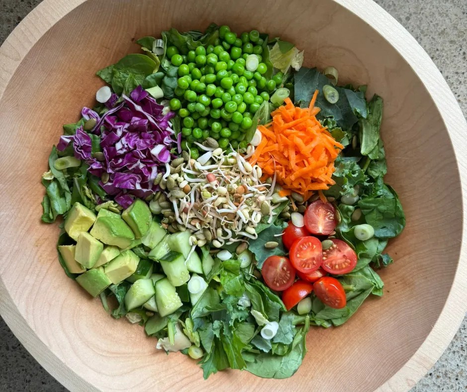 Simple Prep Pesto Garden Bowl with sweet peas, avocado, tomatoes, cucumber, carrots, red cabbage, sprouts, pumpkin seeds, and Creamy Basil Pesto Dressing.