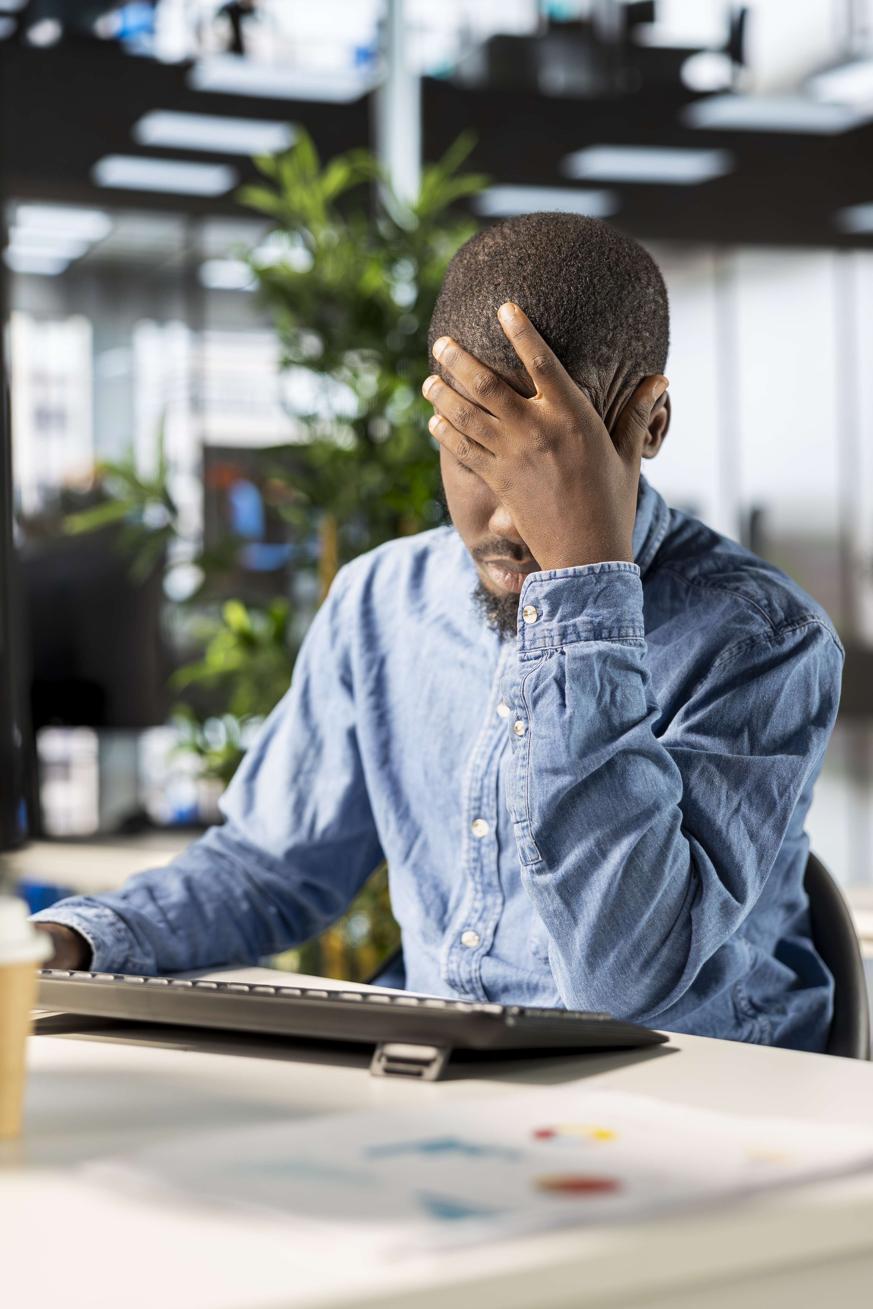 Stressed corporate employee looking down at a table, experiencing workplace burnout and fatigue.