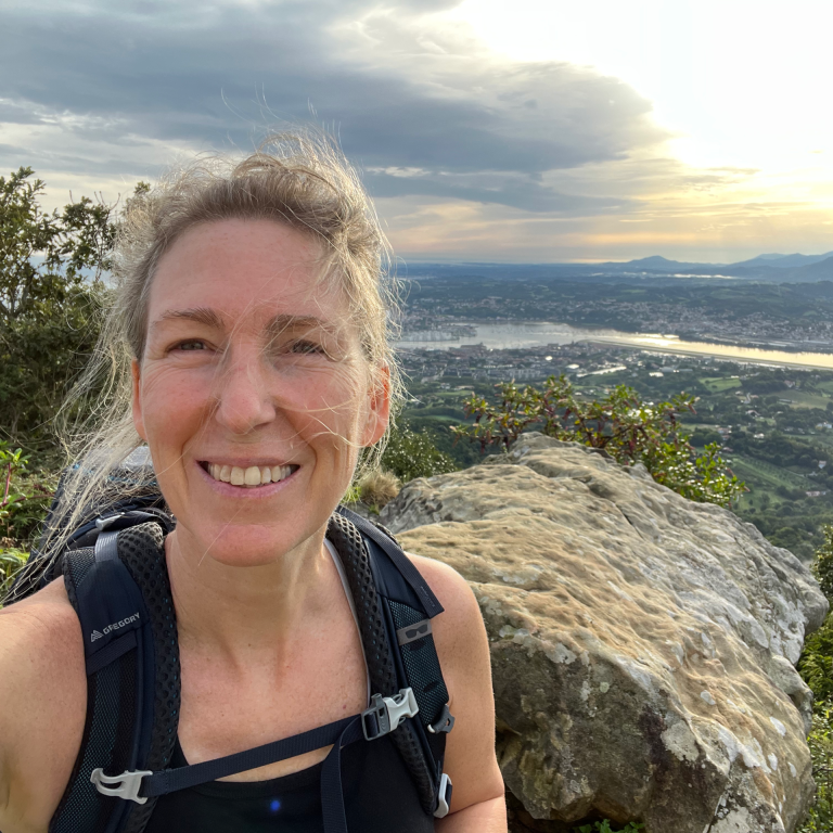 Jo Newman, founder of COLAB 17, smiling outdoors on a mountain trail after successful coaching and collaboration with Linda Bartholme