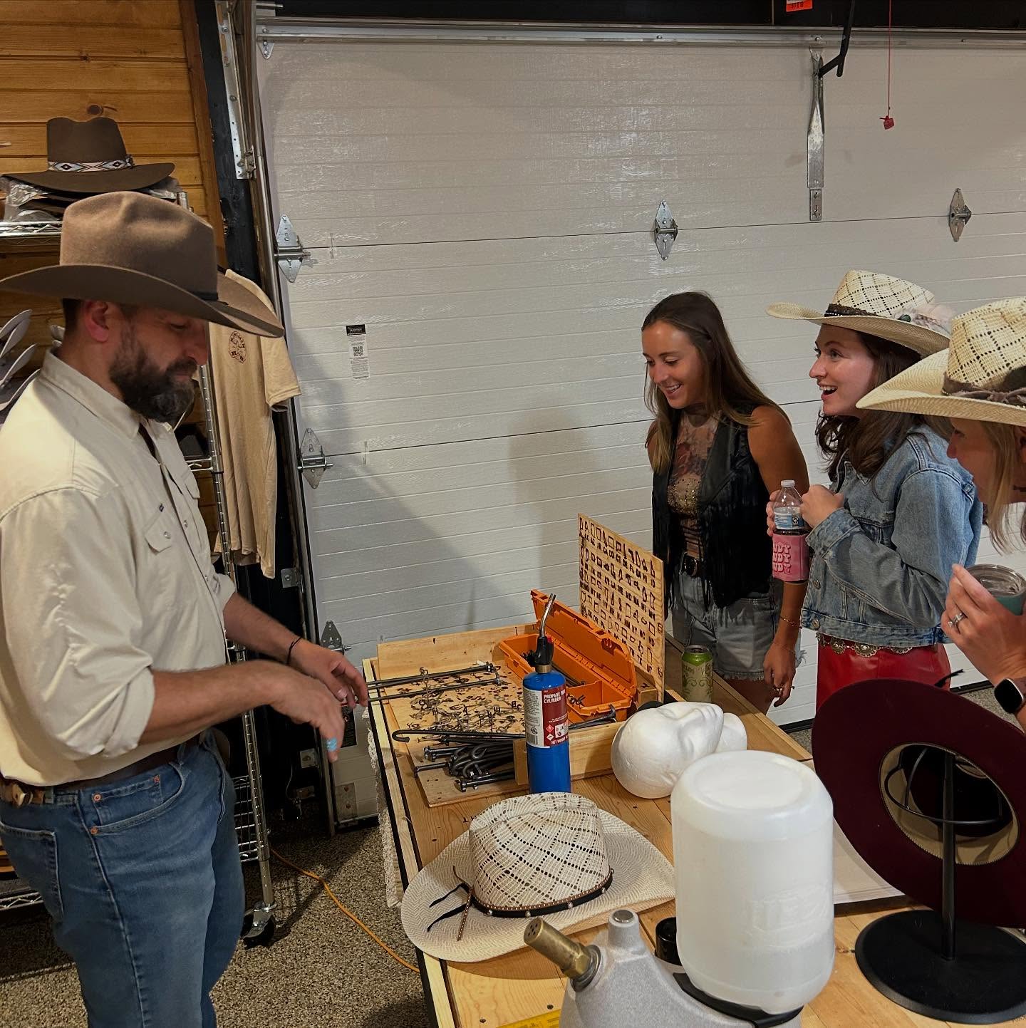 Justin shaping a hat and talking with a guest at an event