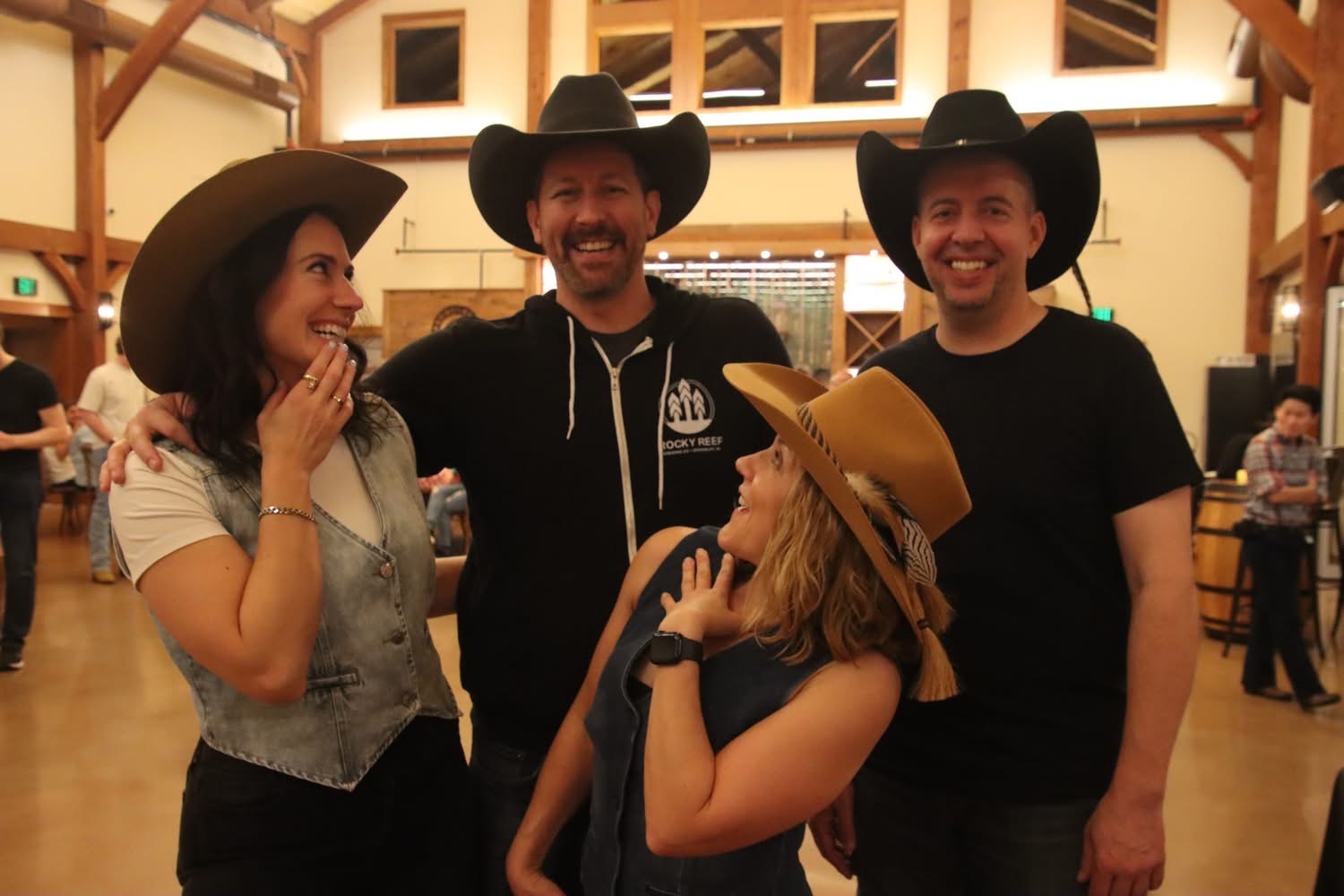 Group of four guests wearing hats and laughing