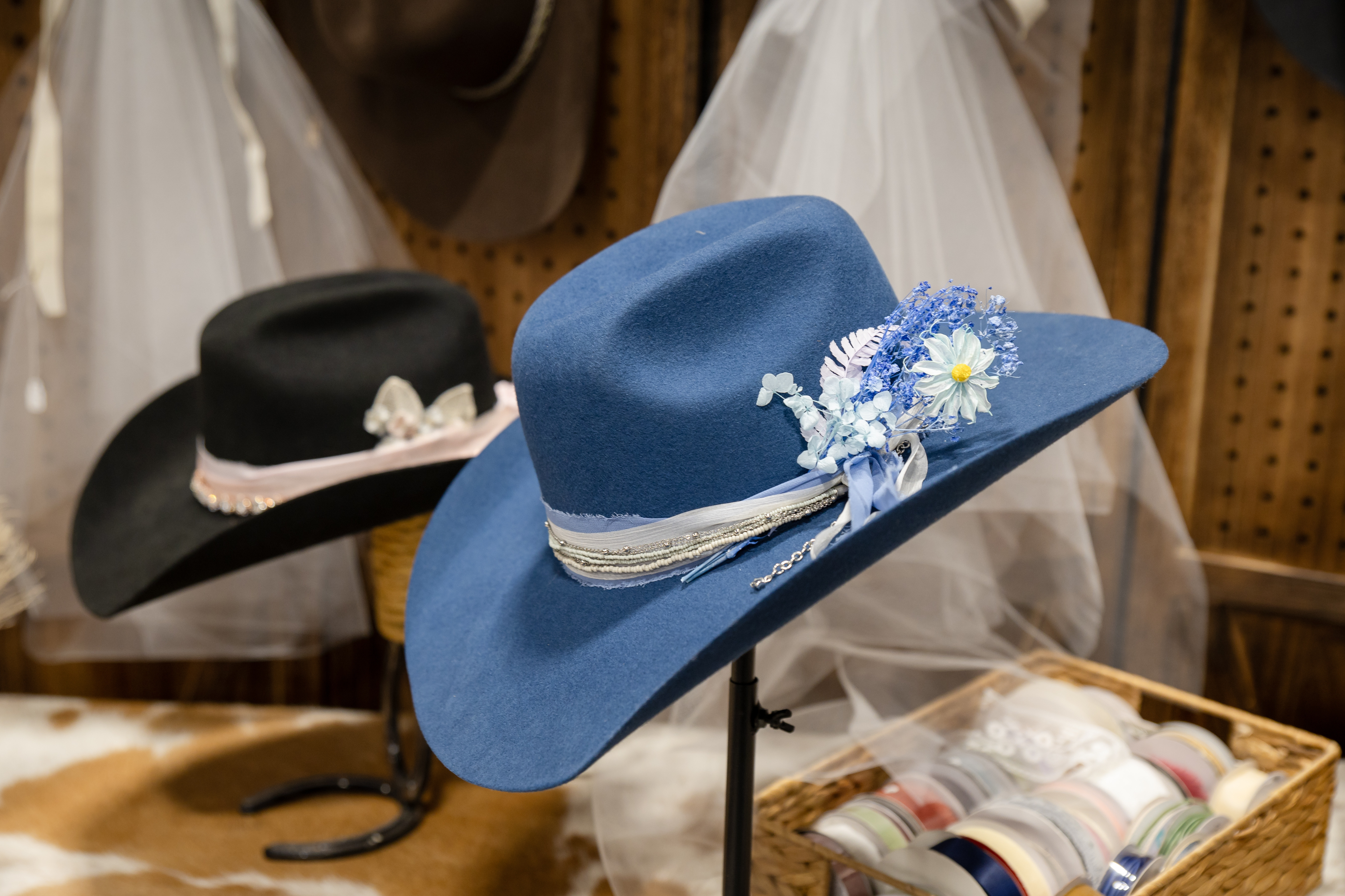 Blue custom hat with a floral veil in the background