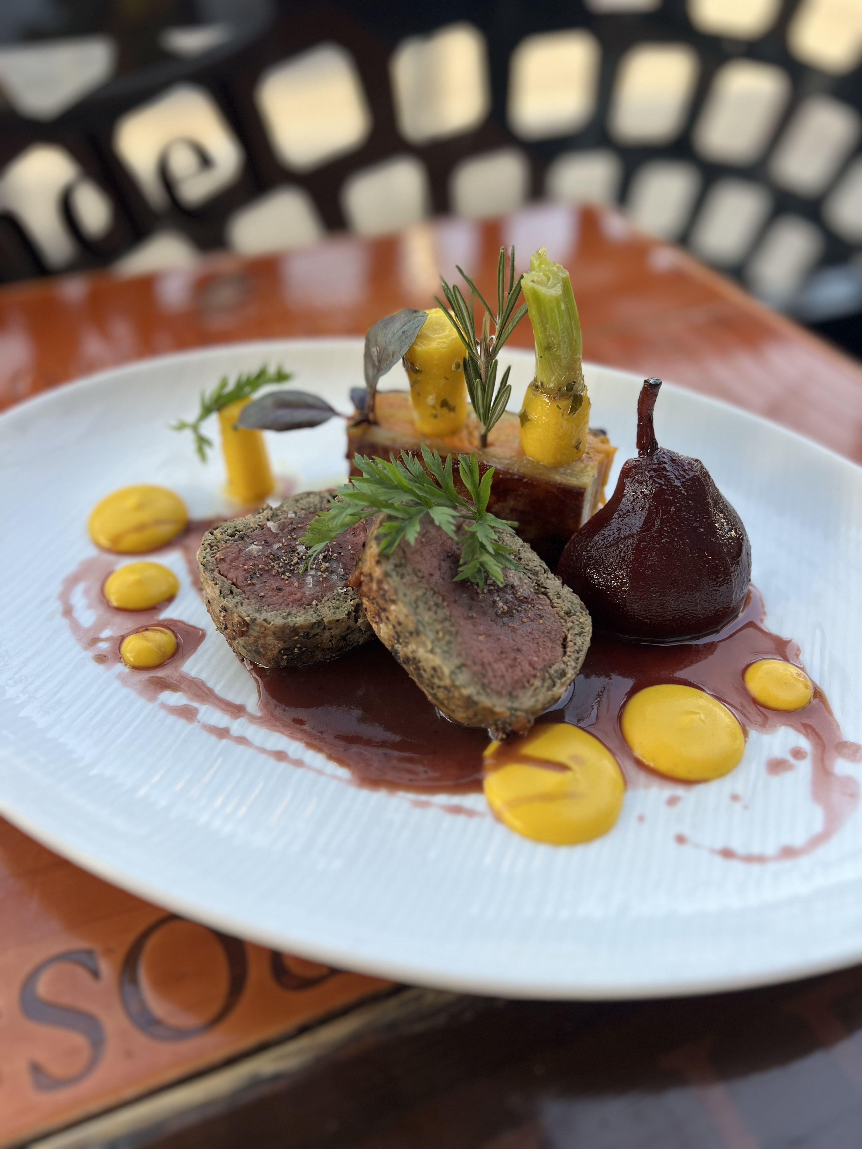 Herb-Crusted Loin with Poached Red Wine Pear at Et Voilà French Bistro