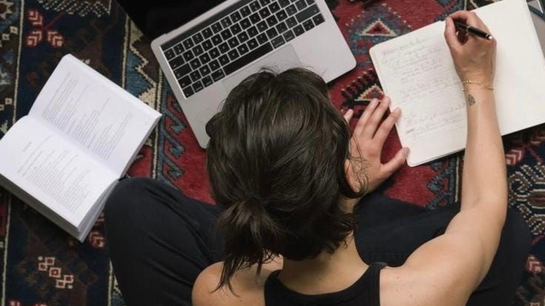 Person working at laptop with multiple documents and notes spread out, representing research, blog writing, and documenting recovery from narcissistic abuse