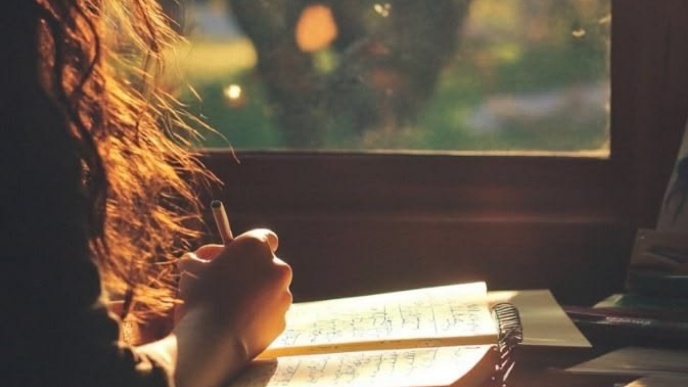 Person journaling by window in warm light, representing grounding techniques, documenting gaslighting, journaling for clarity, and preparing thoughtful responses to narcissistic gaslighting