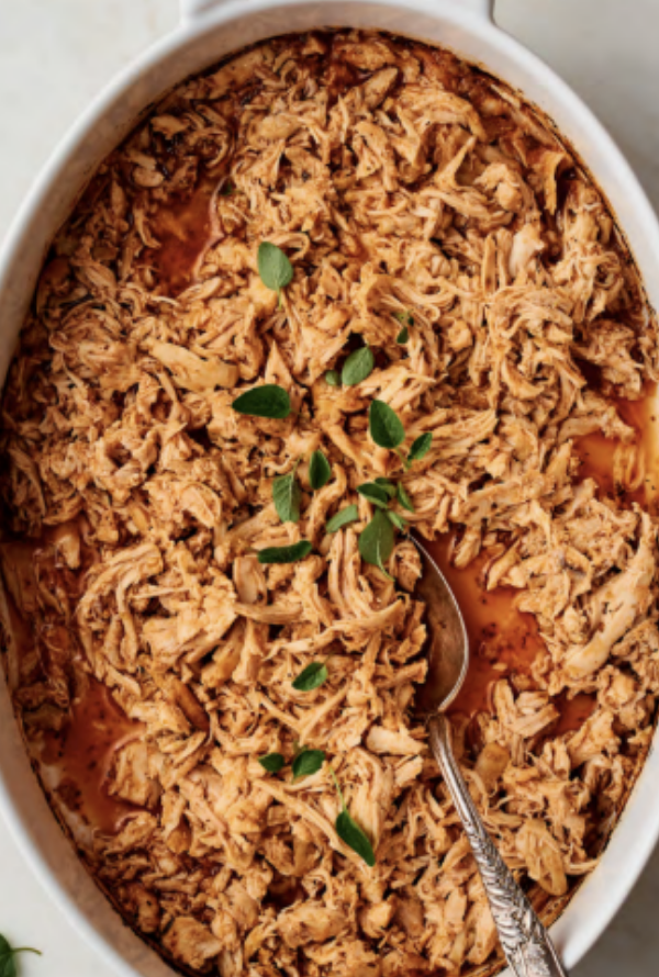 Shredded Lebanese lemon garlic chicken thighs in a casserole dish, 22g protein per portion