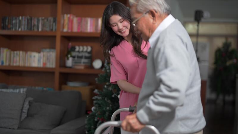  A person walking carefully at home with another person nearby