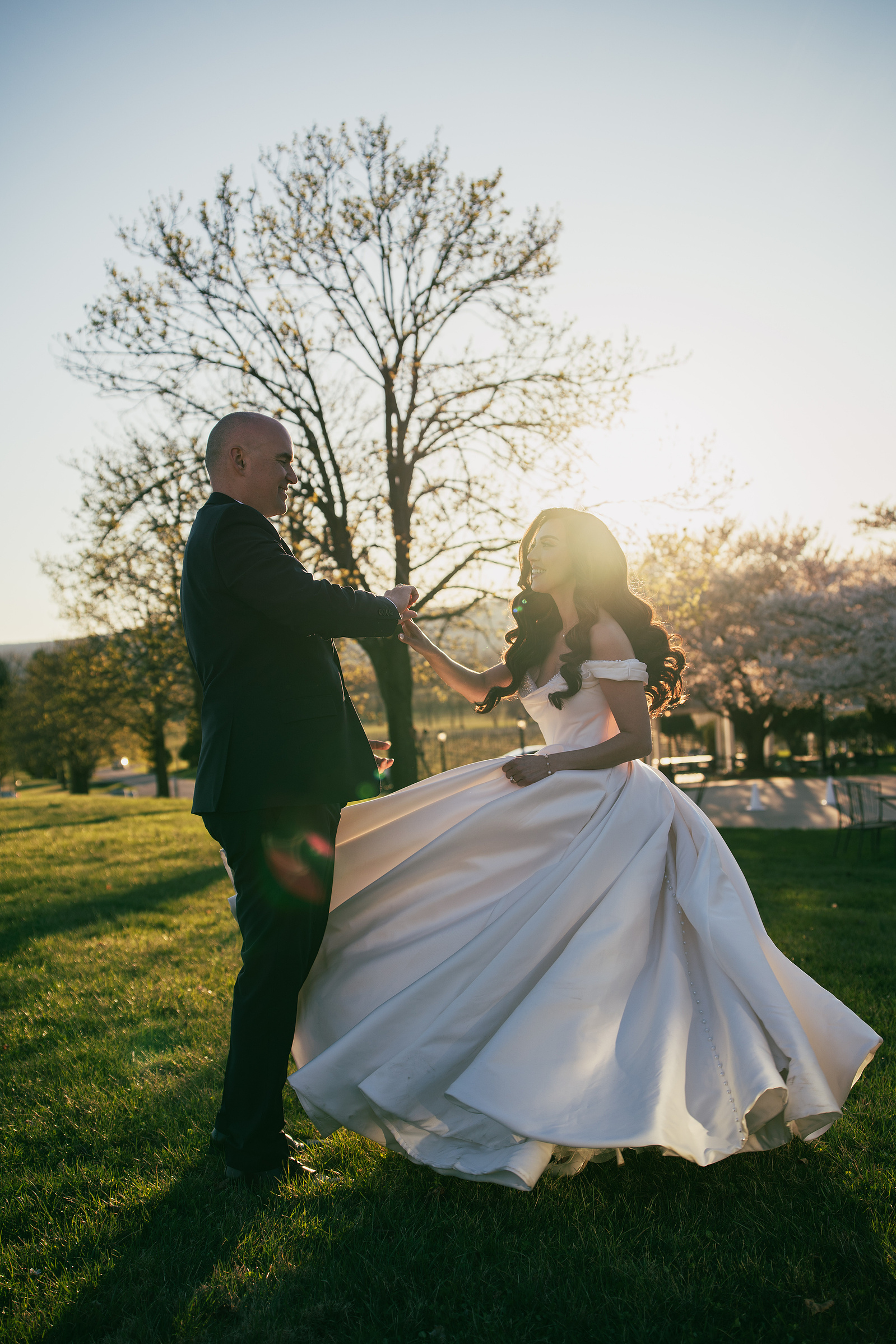A couple dancing on the lawn at sunset on their wedding day