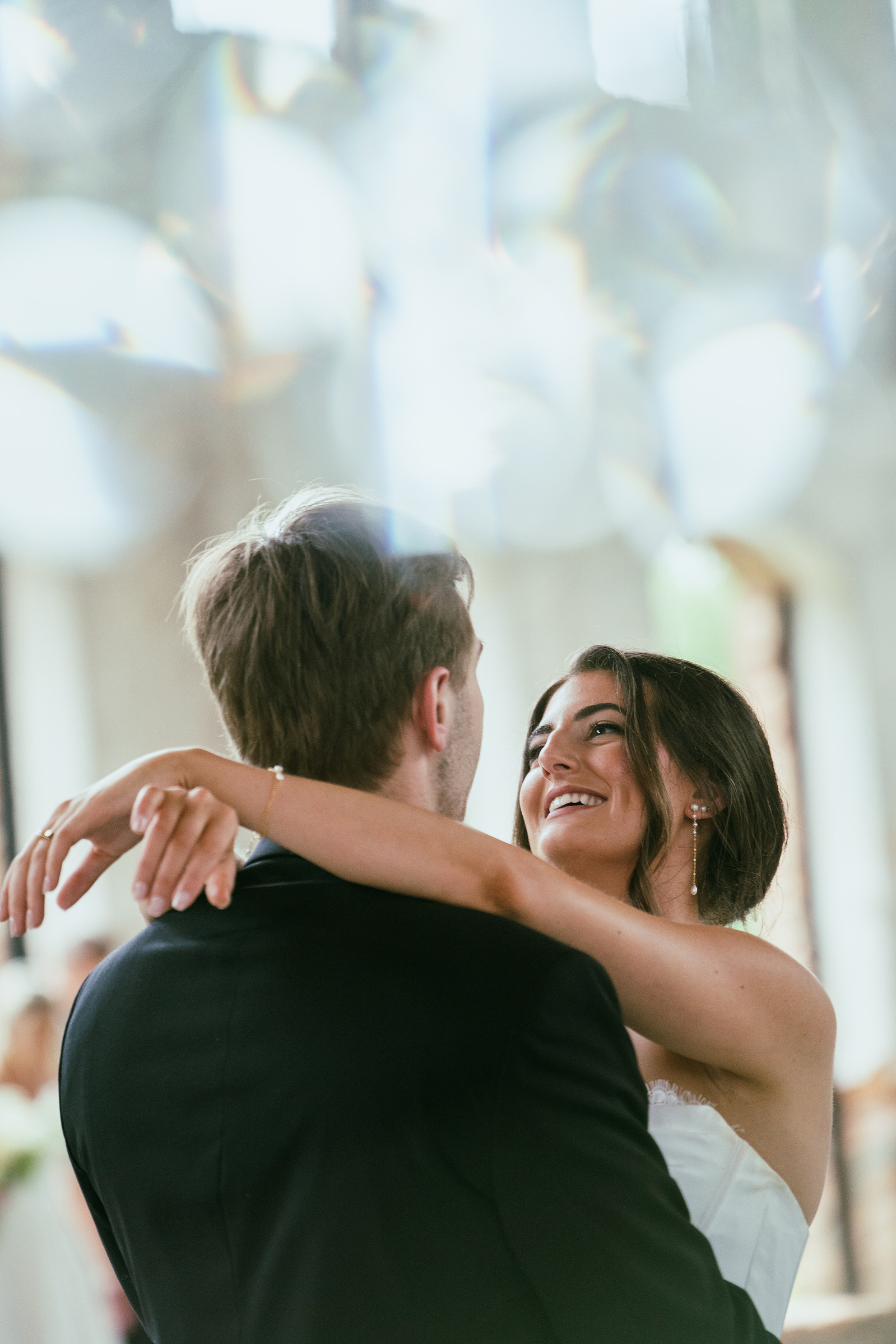 A couple laughing in each other’s arms in soft window light