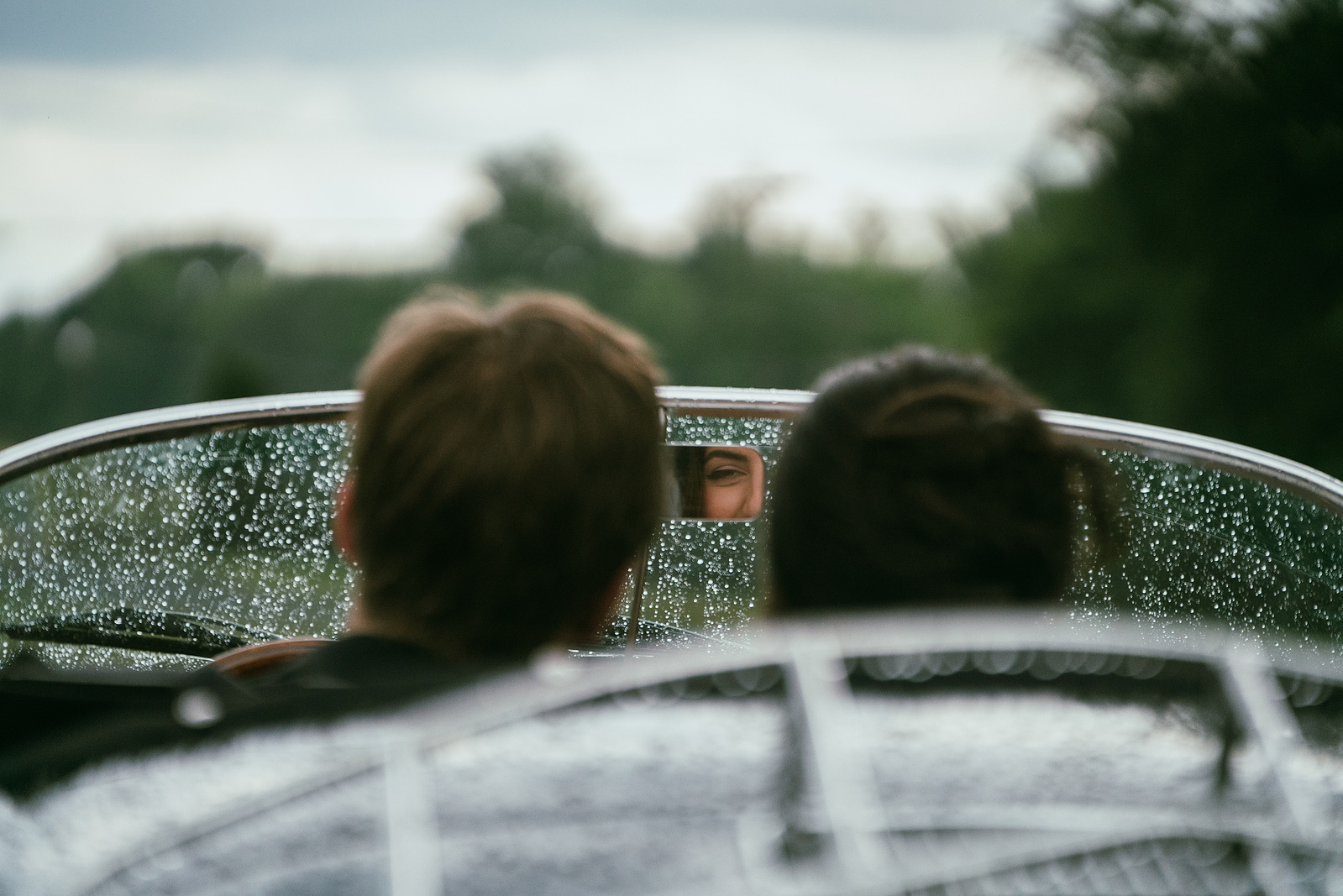 A couple driving away in a vintage convertible after their wedding