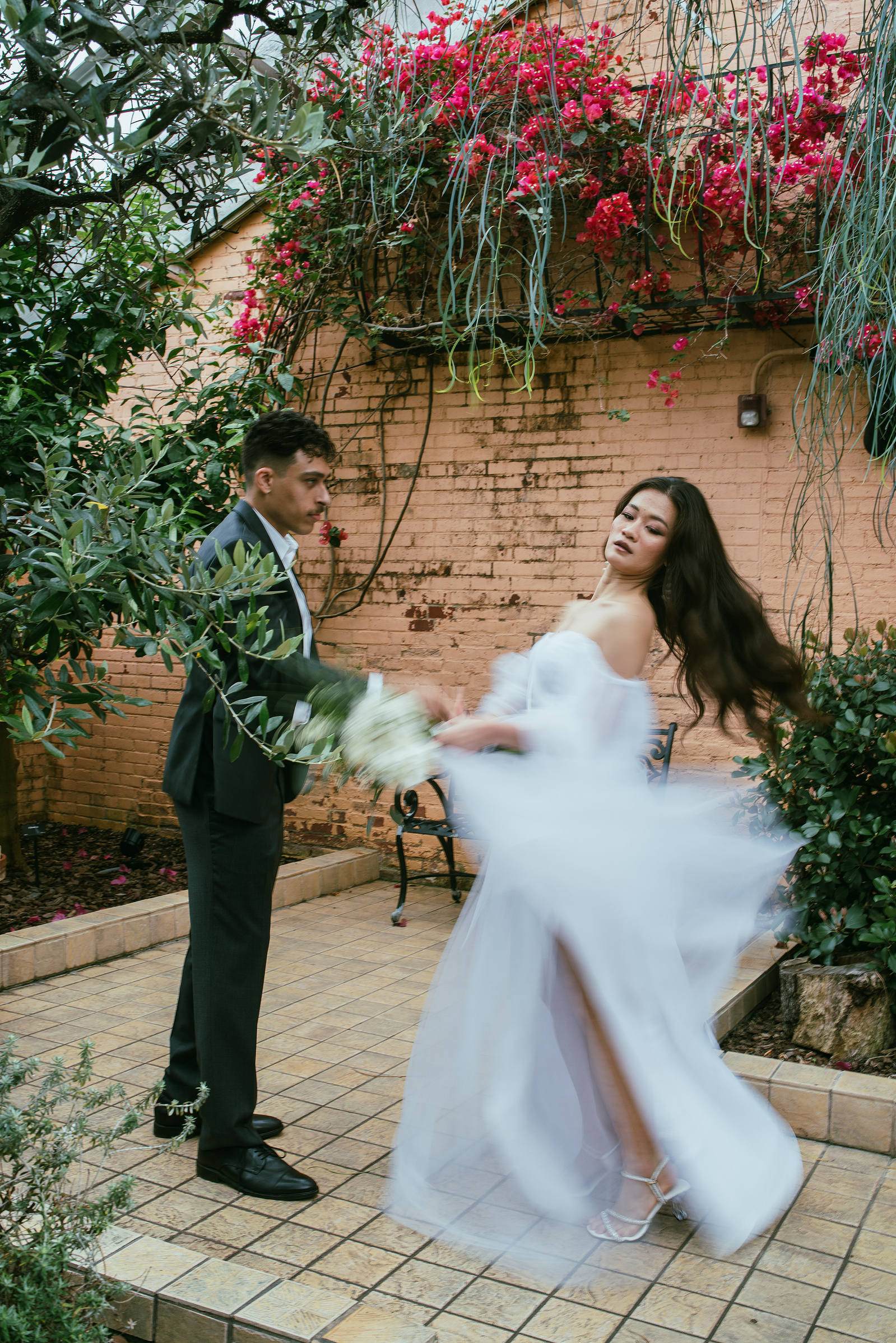 A groom twirling his bride beside a bougainvillea wall at the Rawlings Conservatory in Baltimore