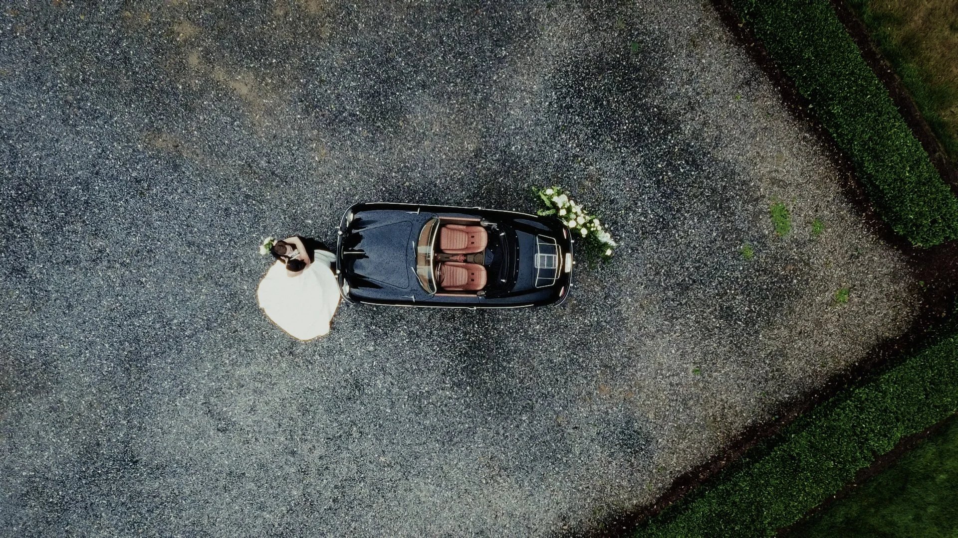 The bride beside a vintage car seen from above, from Makena and Austin's wedding film