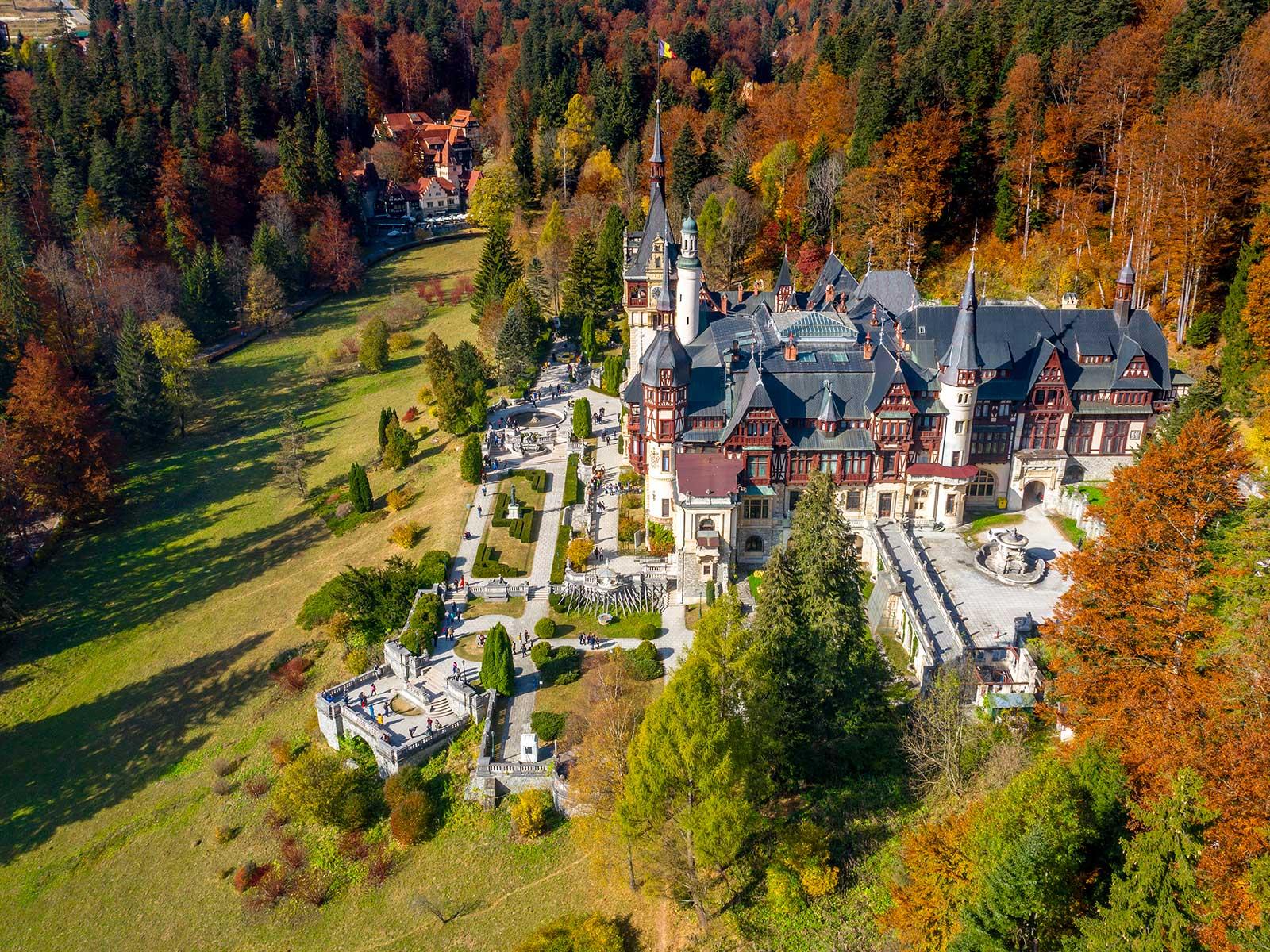 Peleș Castle in Sinaia surrounded by forest and mountain scenery