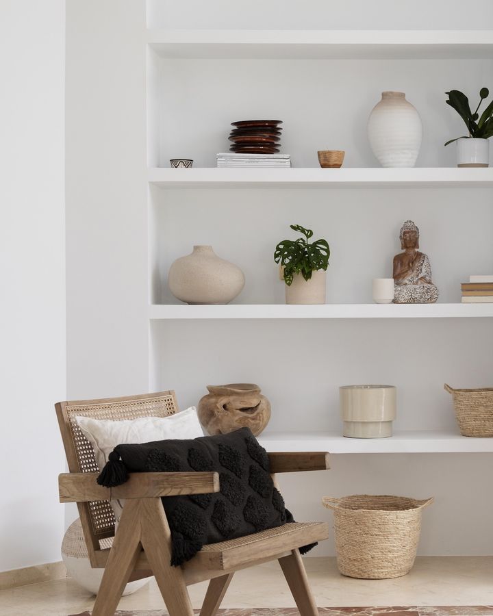 Cane chair beside styled white built-in shelves