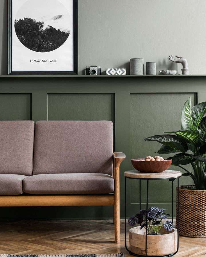Staged living room with a wood-frame sofa and green paneled wall