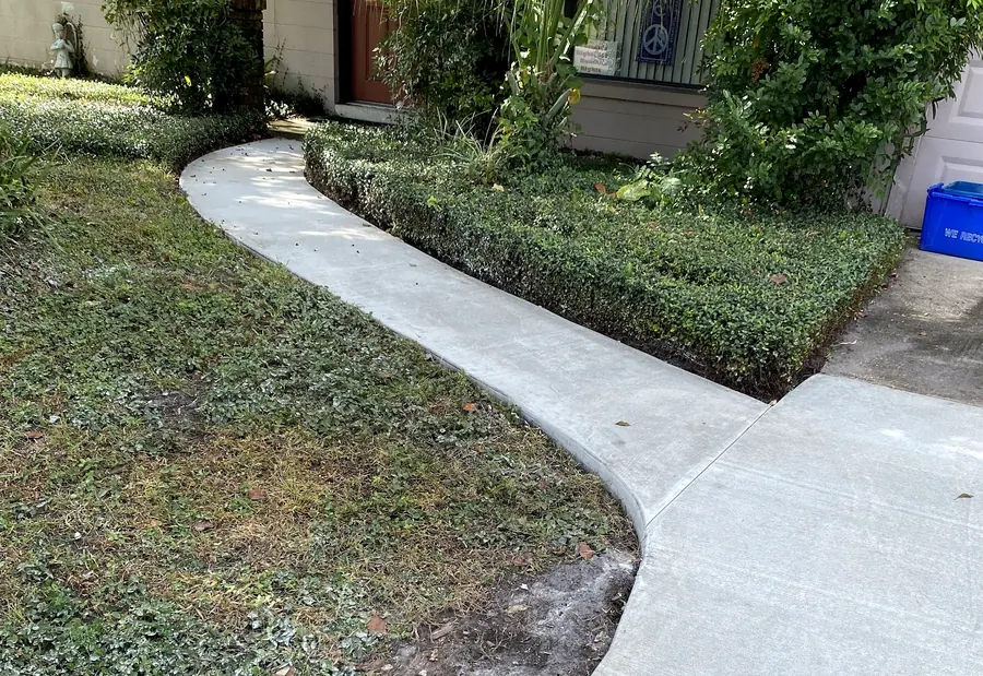 New curved concrete walkway through a front yard to the house