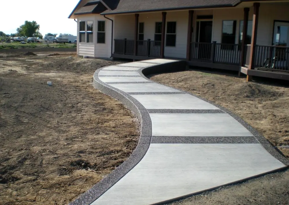 Curved concrete walkway with a dark stone border leading to a front porch