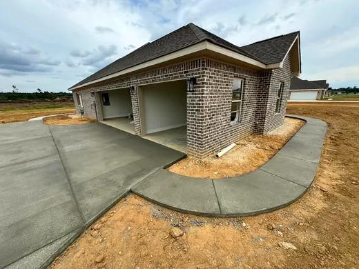 Fresh concrete driveway and curved walkway at a new brick home