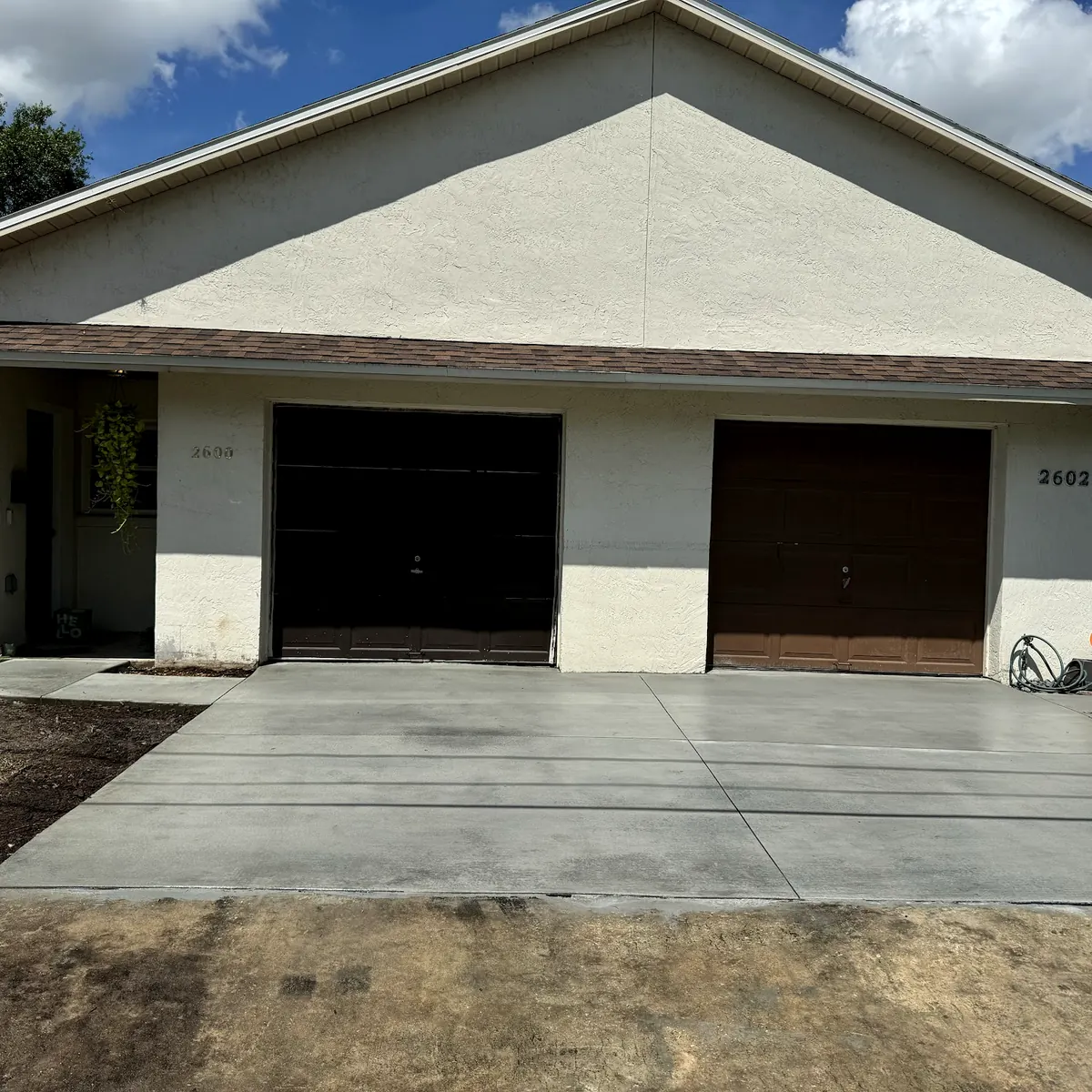 New concrete driveway poured in front of a two-car garage