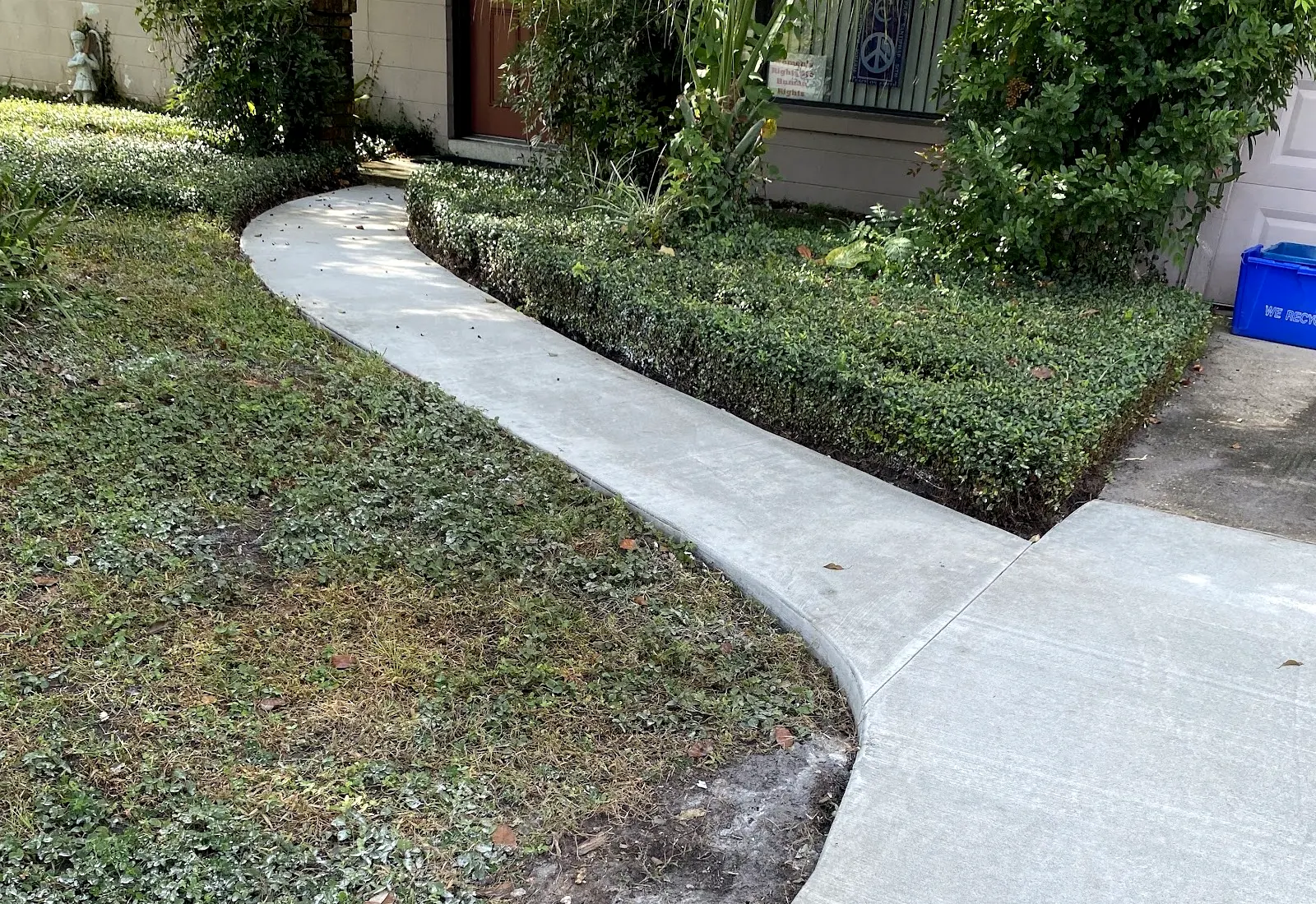 New curved concrete walkway through a front yard to the house