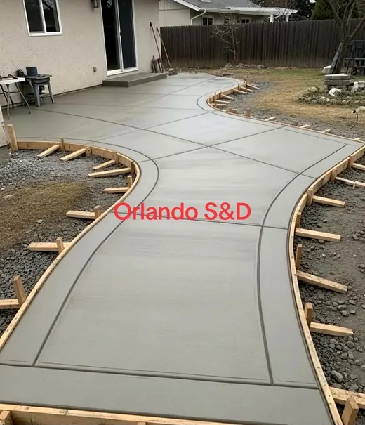 New concrete patio and curved path behind a house with the forms still in place