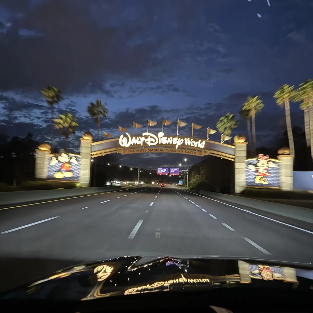 Driving toward the Walt Disney World entrance sign at night