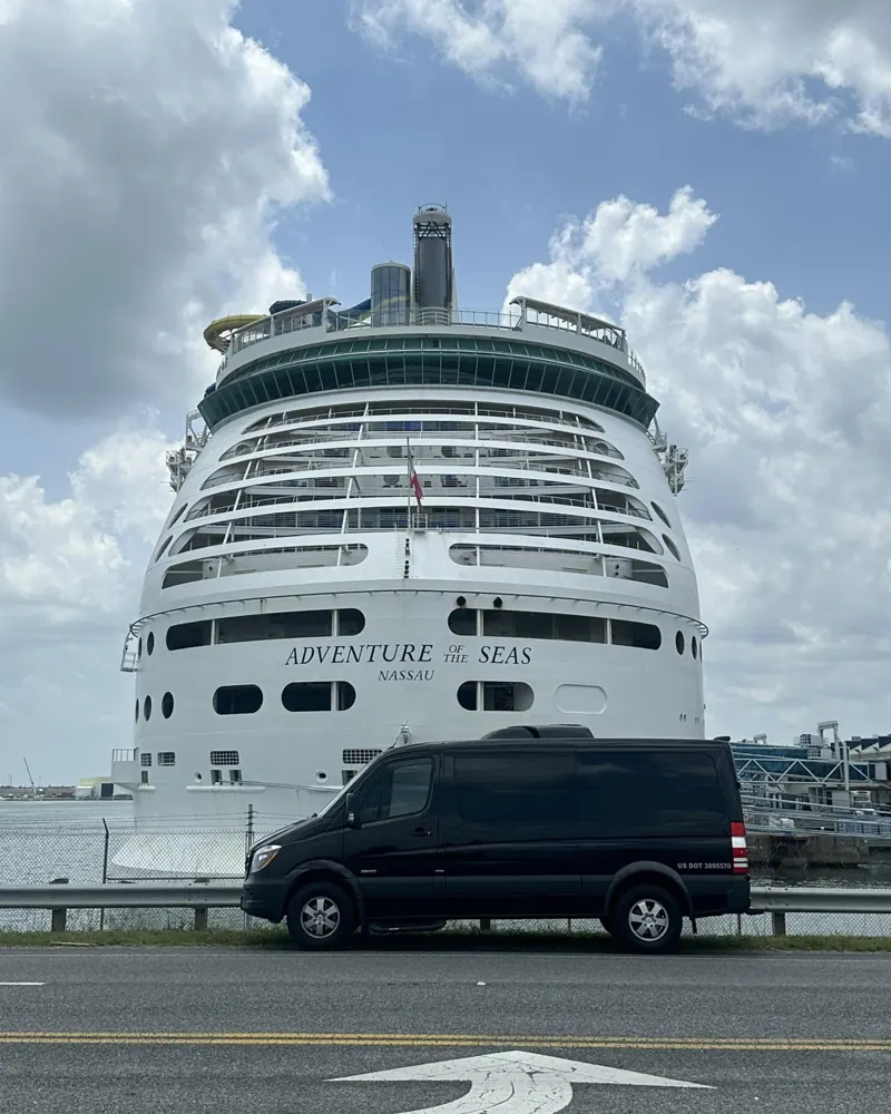 Black passenger van parked in front of the Adventure of the Seas cruise ship