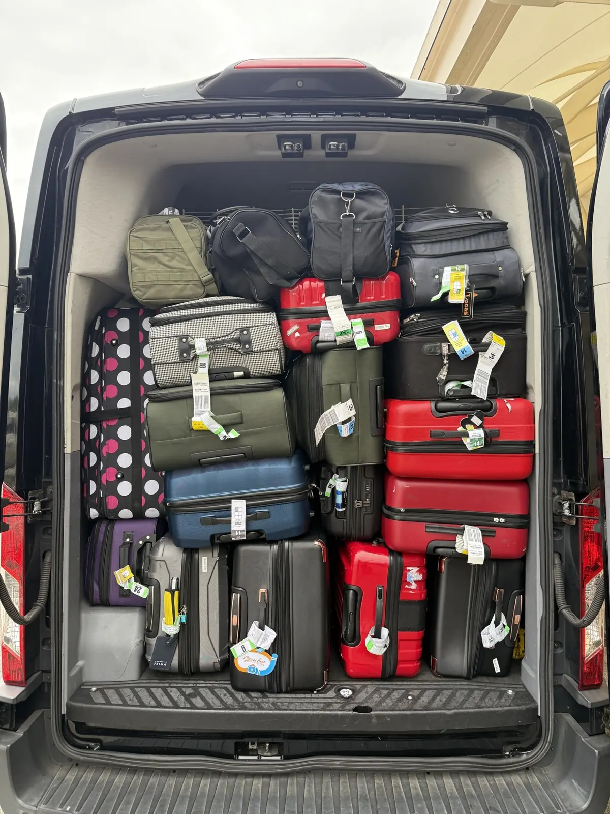 Van with its rear doors open, packed with suitcases