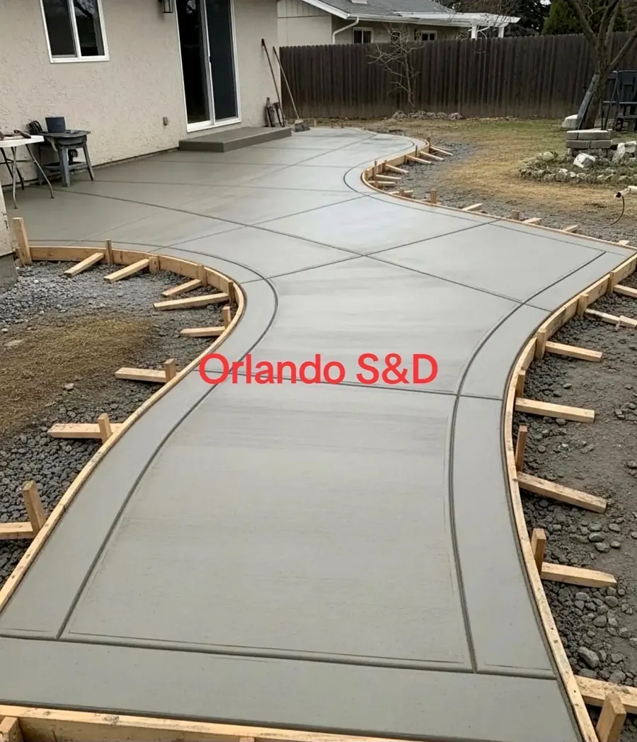New concrete patio and curved path behind a house with the forms still in place