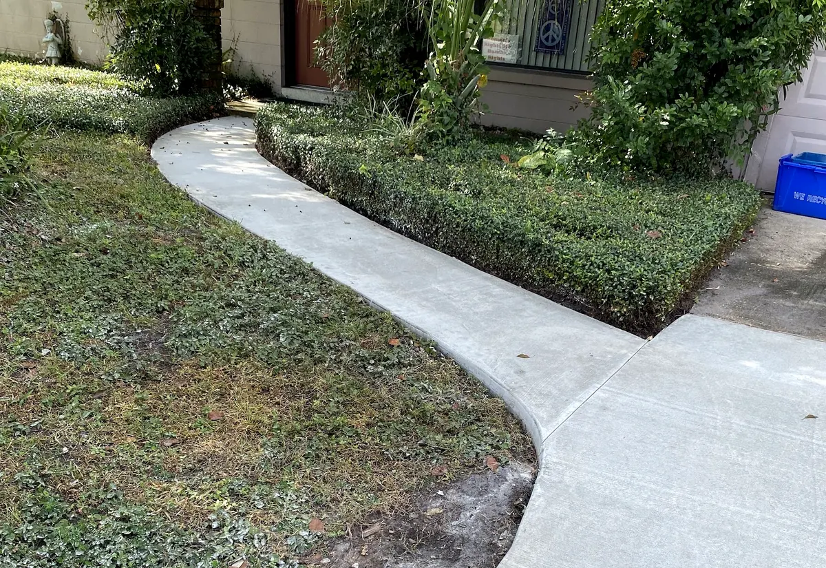 New curved concrete walkway through a front yard to the house