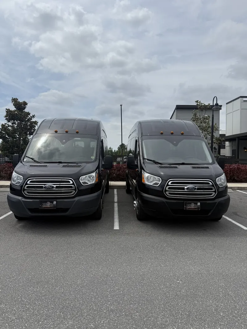 Two black Ford Transit passenger vans parked side by side