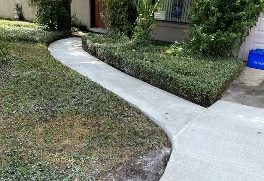 New curved concrete walkway through a front yard to the house