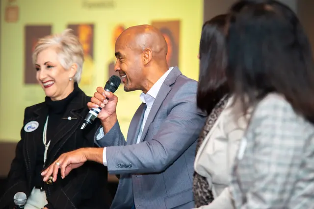 Reggie Carney speaking with a microphone among event attendees