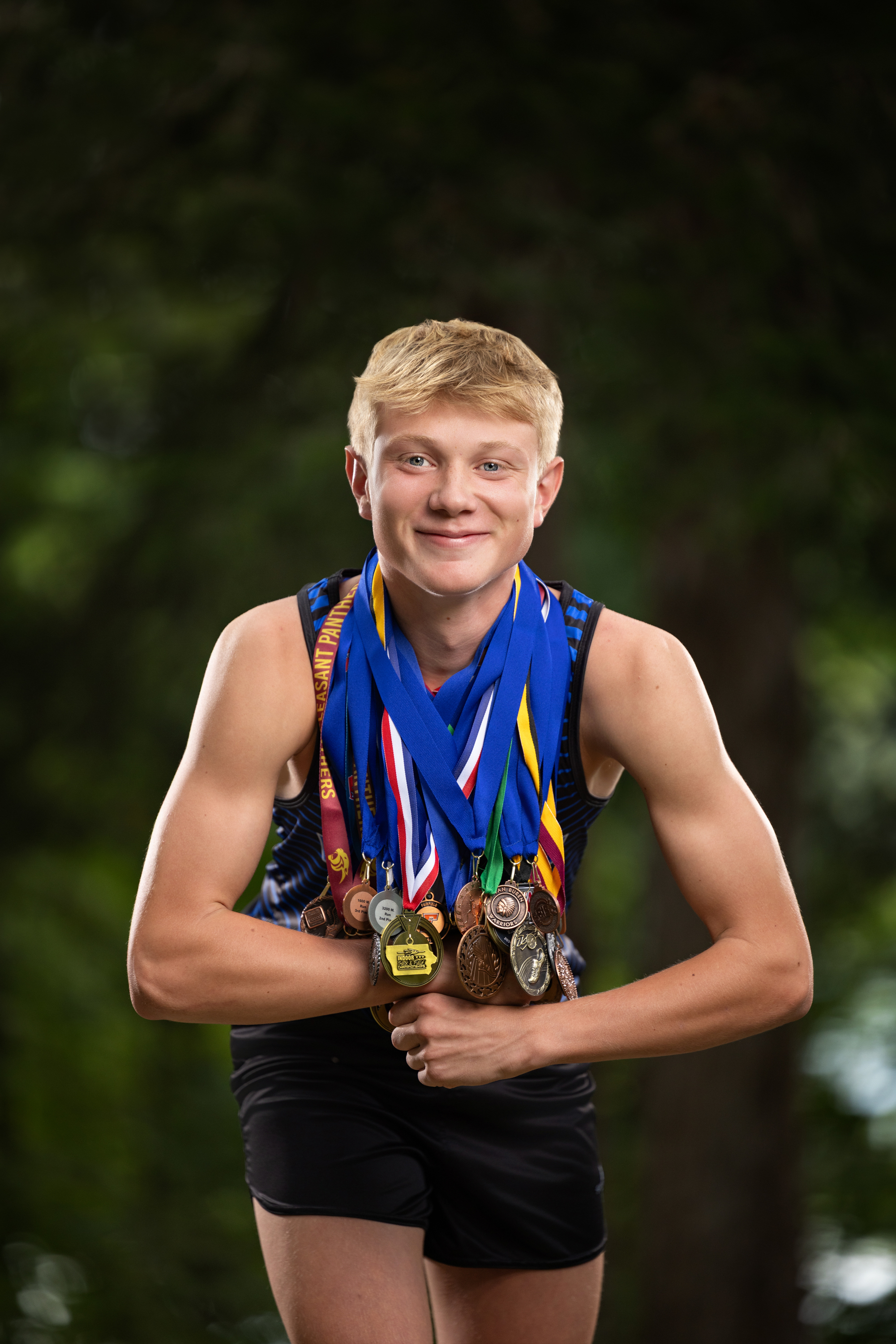 high school senior isaac with all of his cross country medals
