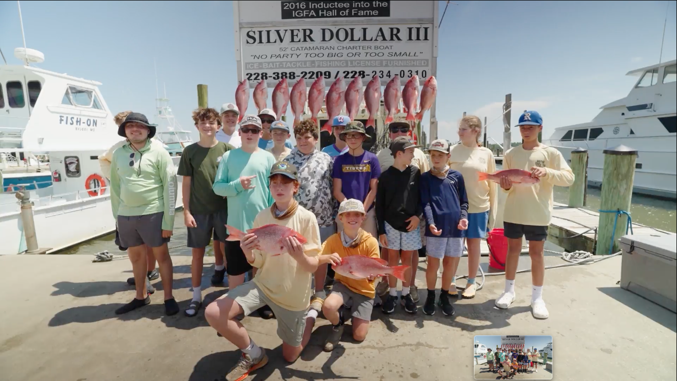 A group of young anglers on the dock holding red snapper they caught