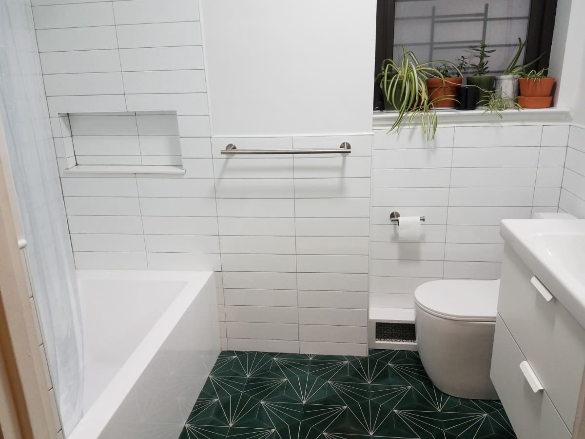 Modern bathroom with waterproofed white tiles and green geometric patterned floor.