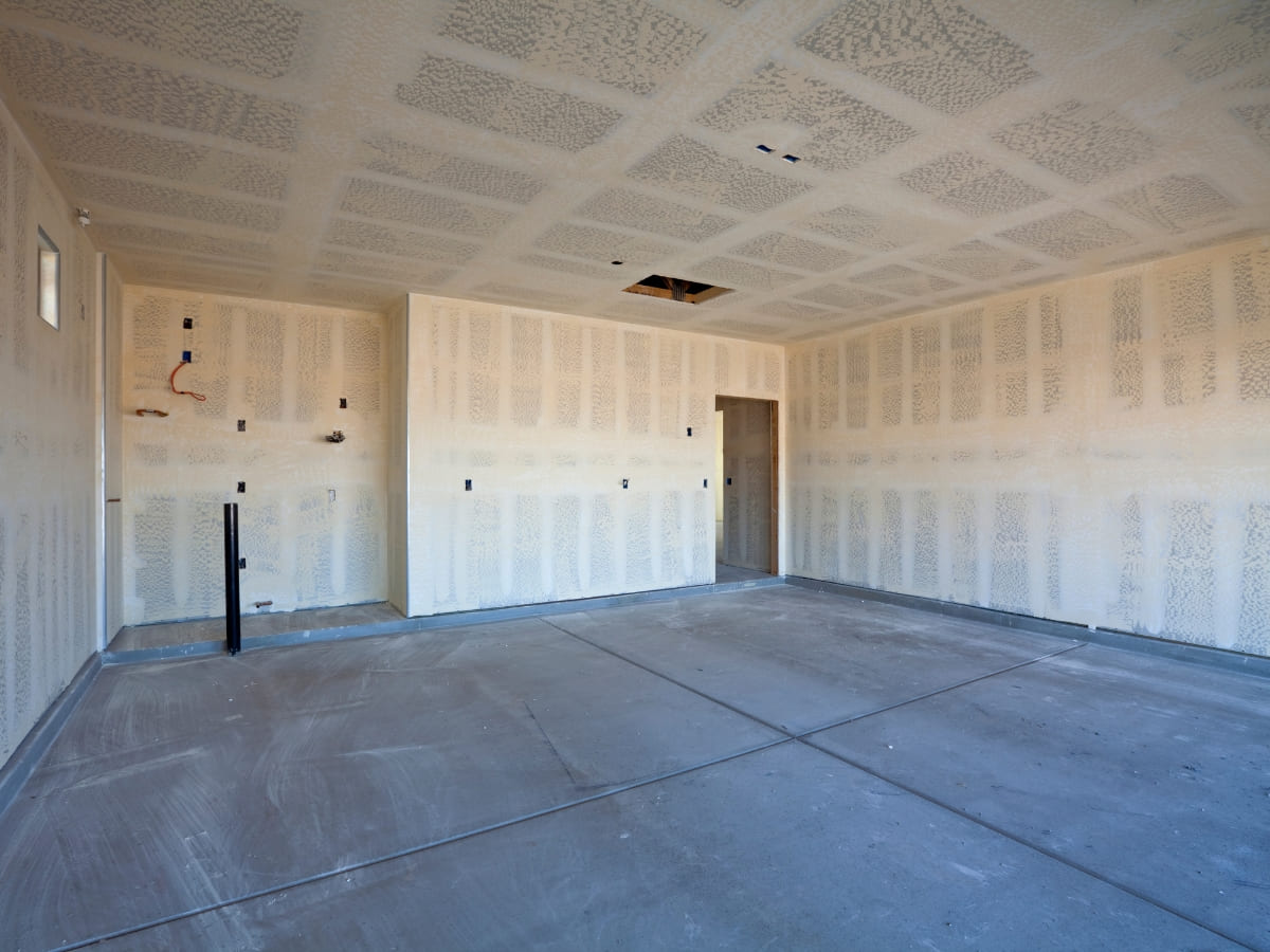  newly constructed garage space with freshly installed sheetrock on the walls and ceiling, ready for further finishing.