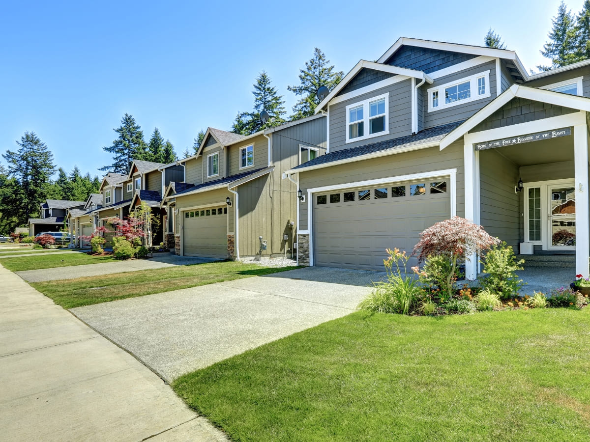 A suburban neighborhood featuring homes with neatly paved concrete driveways and well-kept lawns, emphasizing a clean and uniform appearance.