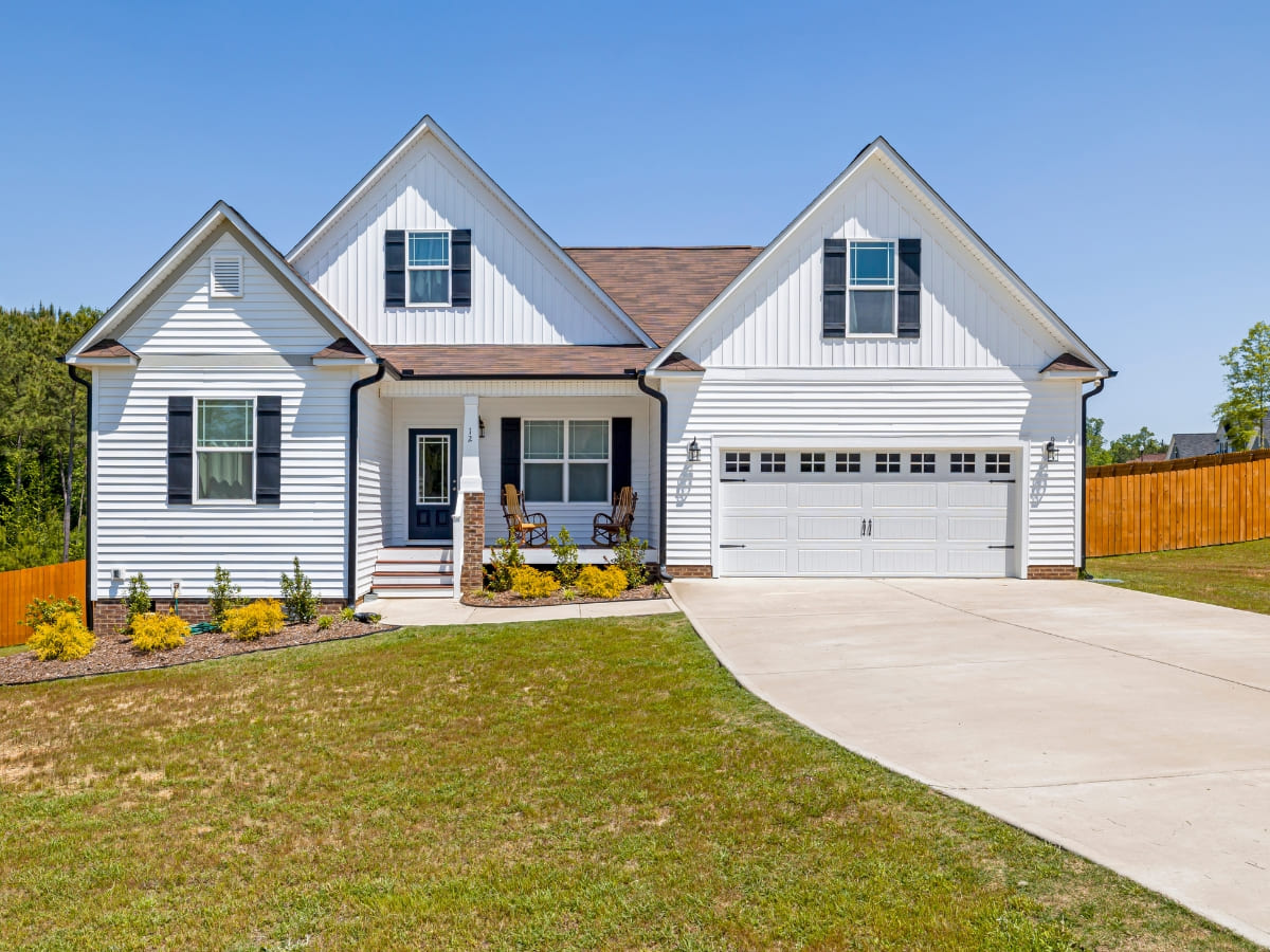 A single-family home with a wide, smoothly finished concrete driveway leading up to a two-car garage, framed by well-manicured landscaping.