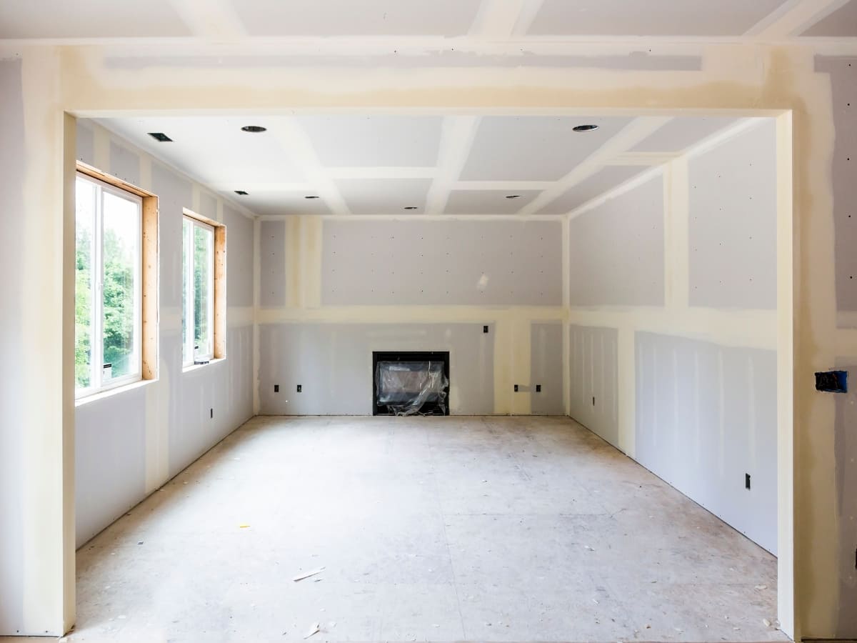 A newly constructed living room with drywall installed and seams taped, ready for the next stage of finishing.