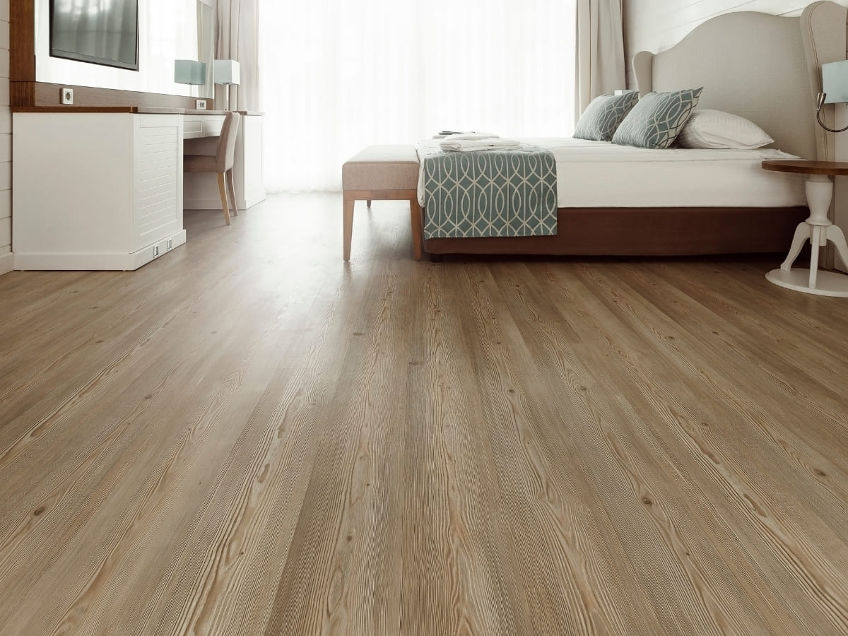 Bedroom with light wood vinyl flooring, a bed with a patterned bedspread, and modern decor.