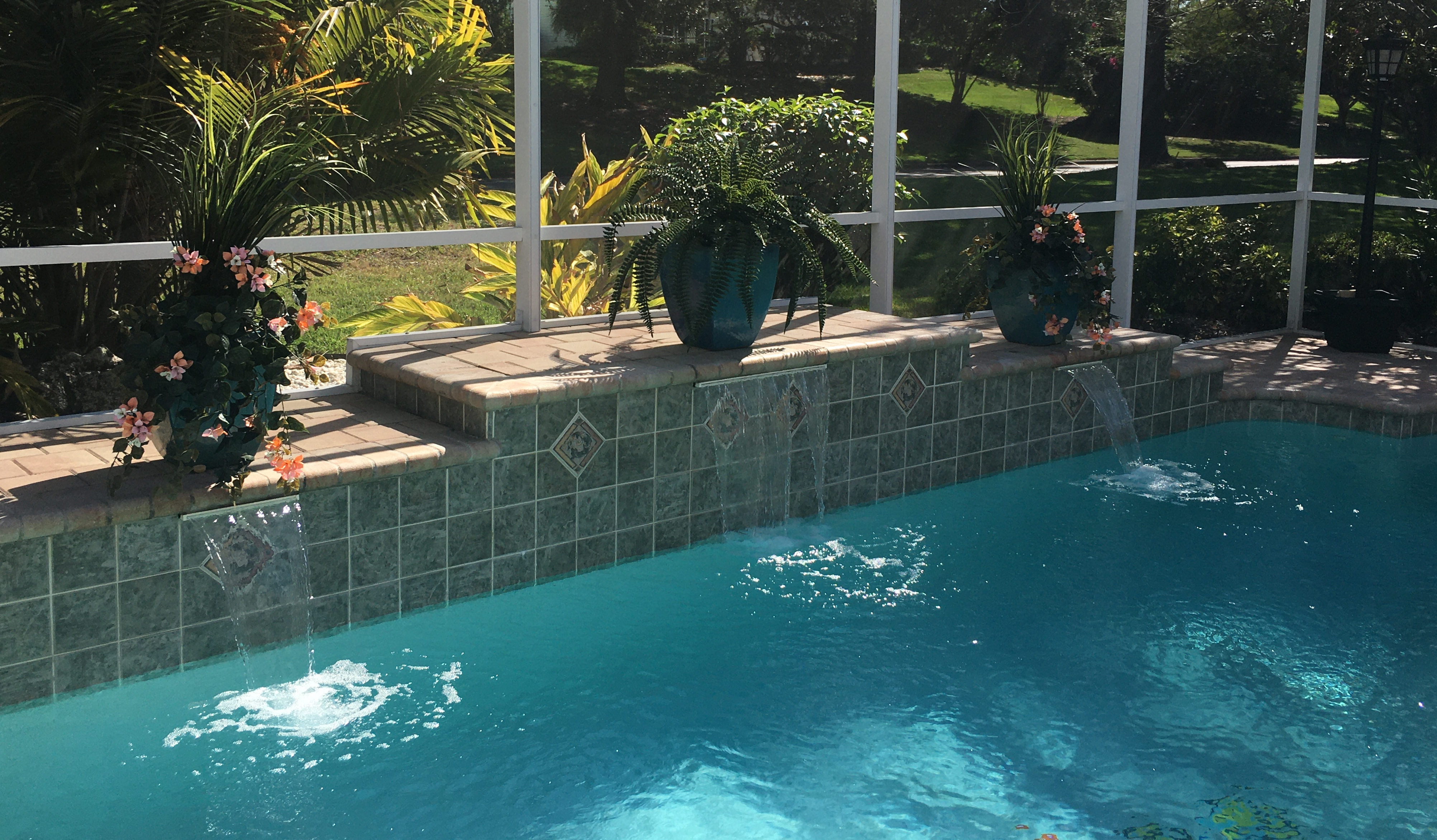 Outdoor artificial plants, ferns and flowers in planters around pool