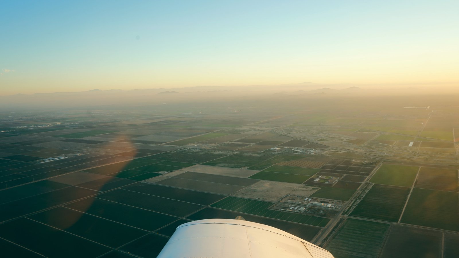 View over a Piper wing across the farmland of the Phoenix East Valley at sunrise