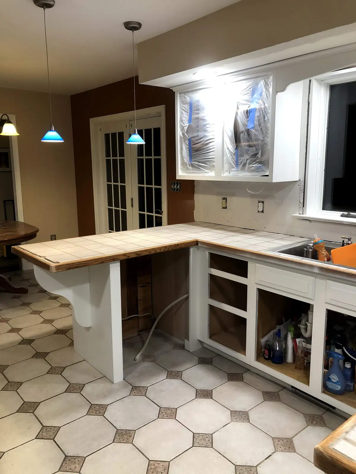 A kitchen remodel showcasing white cabinets, a tiled by Webster Custom...