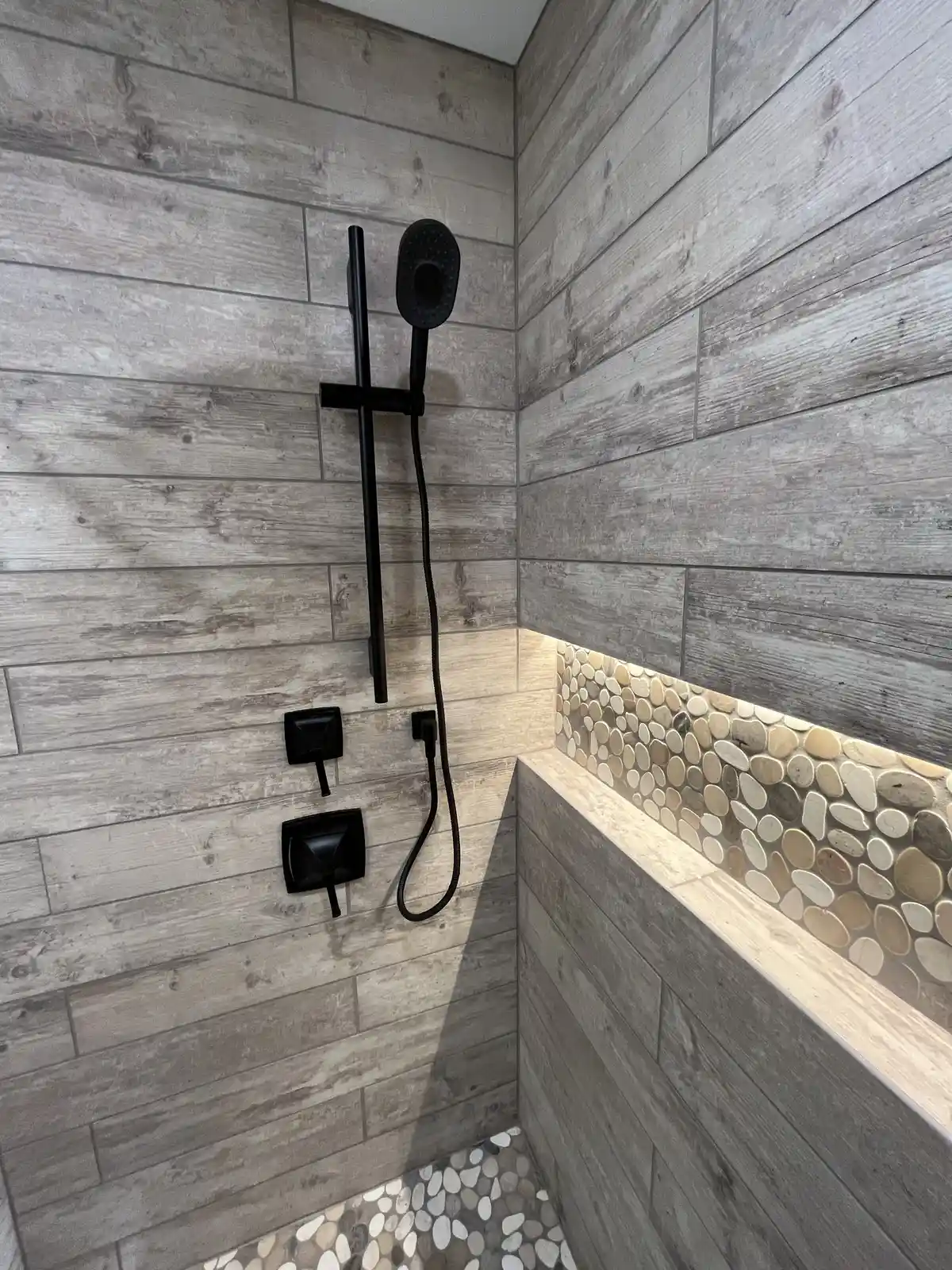 62 Candy Rd, Mohnton, PA 19540: A modern shower remodel at 62 Candy Rd featuring wood-look tile walls, black by Webster Cu...