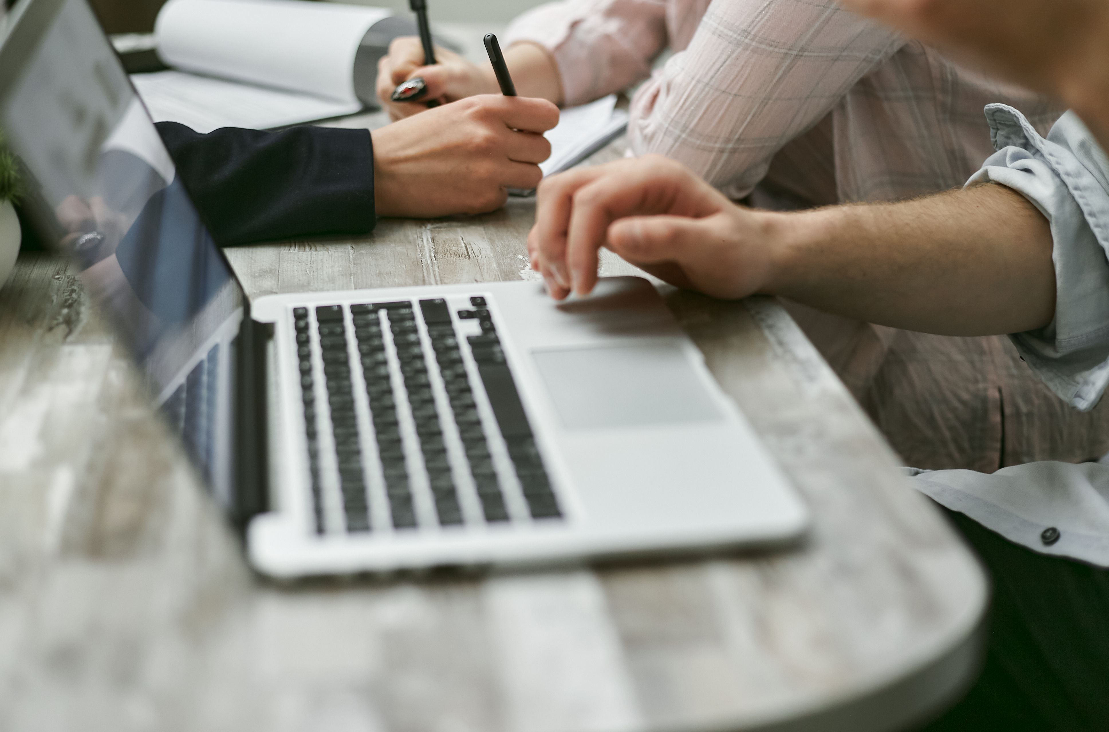 unrecognizable coworkers using laptop and writing information on papers